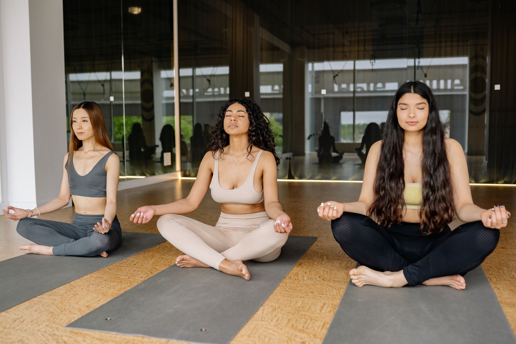 Three women sharing a quiet meditation practice in a light-filled studio